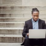 Network Building - Focused ethnic businessman browsing laptop on stairs