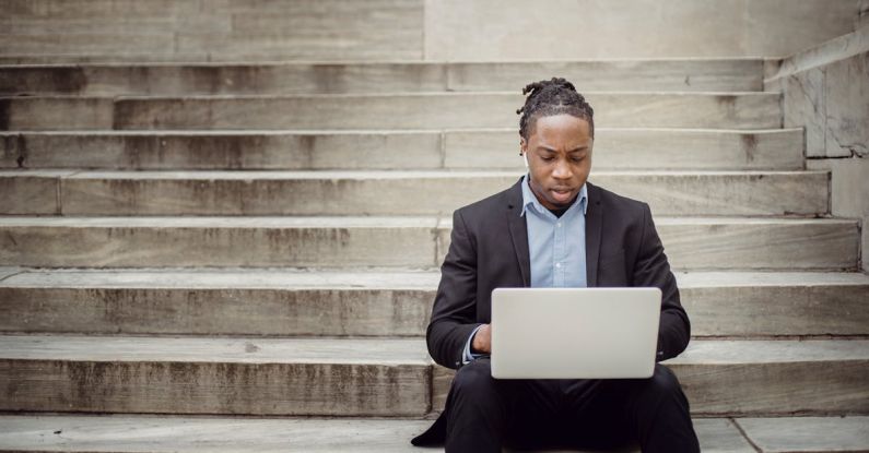 Network Building - Focused ethnic businessman browsing laptop on stairs