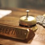Hospitality - Old fashioned golden service bell and reception sign placed on wooden counter of hotel with retro interior