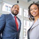 Business Attire - Man and Woman Smiling Inside Building